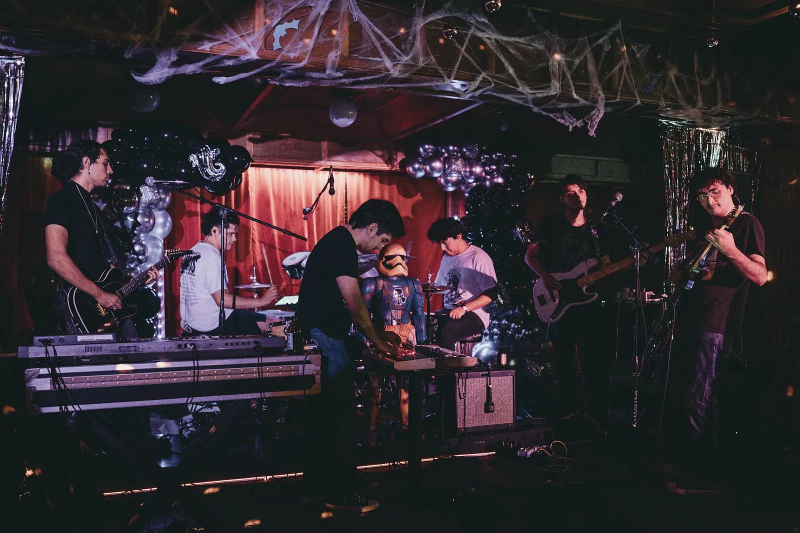 Vertigo performing on a small stage under magenta light