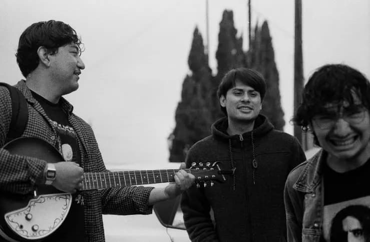 Integrantes de Vertigo riendo mientras tocan guitarra al aire libre